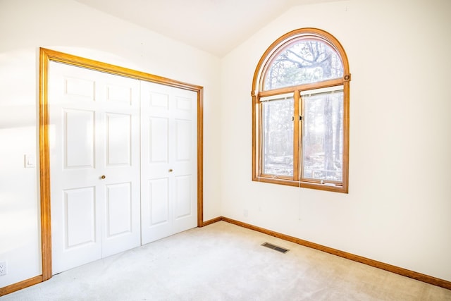 unfurnished bedroom featuring a closet, vaulted ceiling, and light carpet