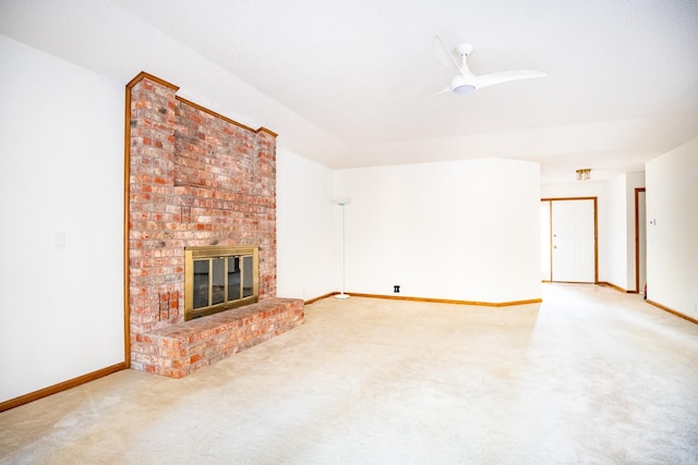 unfurnished living room with a brick fireplace, ceiling fan, and carpet flooring