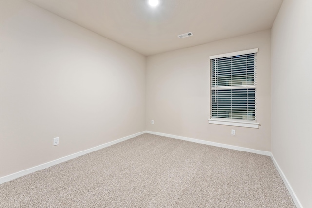 carpeted spare room featuring baseboards and visible vents