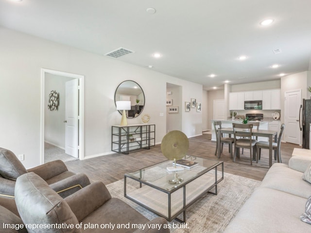 living area with visible vents, recessed lighting, baseboards, and wood finished floors