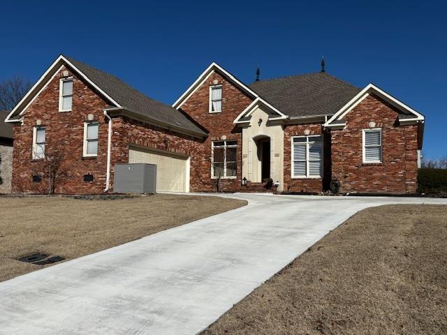 view of front property with a garage, cooling unit, and a front lawn