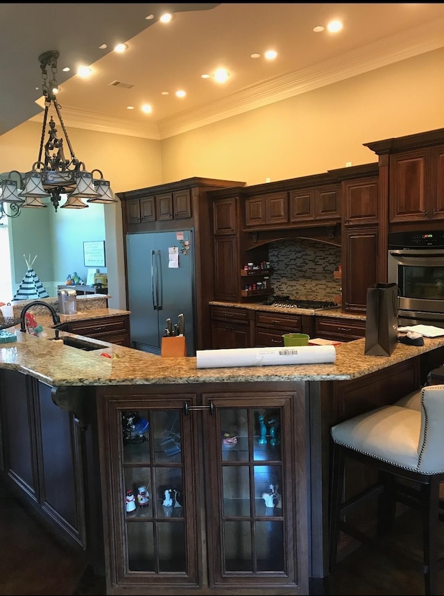 kitchen with sink, dark brown cabinetry, pendant lighting, stainless steel appliances, and a breakfast bar area