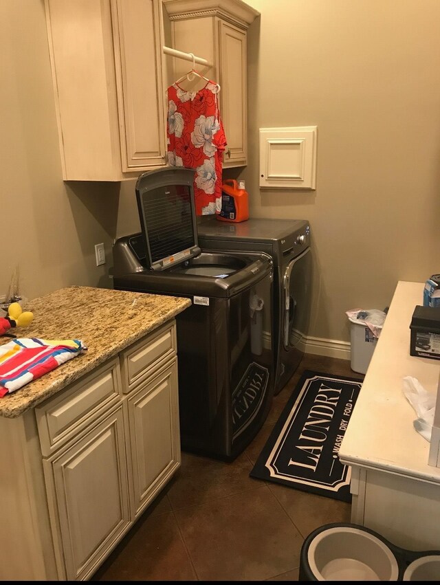 clothes washing area with cabinets, washer and dryer, and dark tile patterned floors