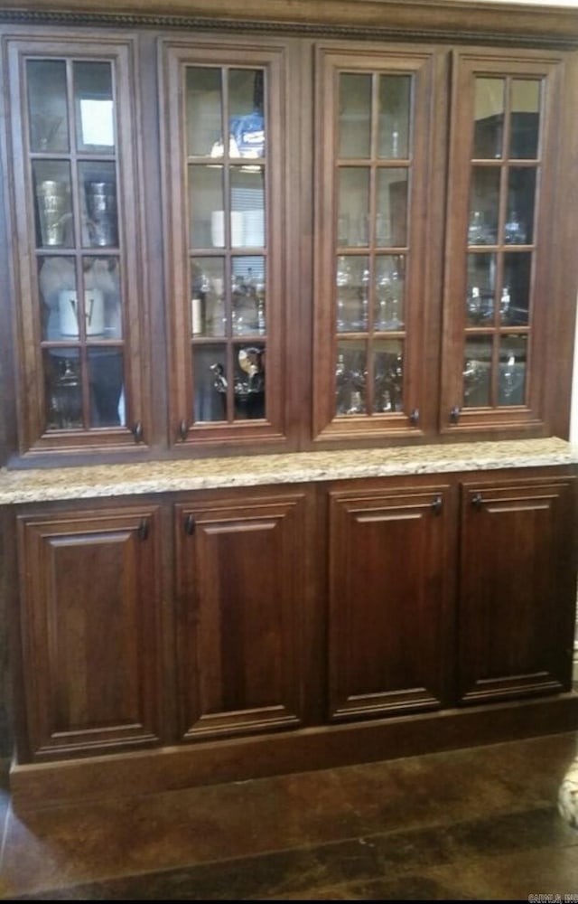 bar with dark brown cabinetry and light stone counters