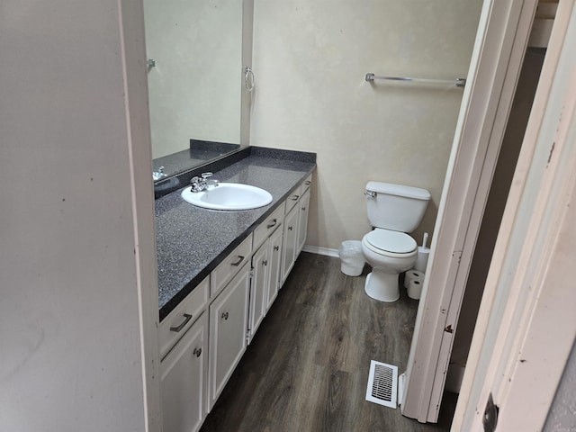 bathroom with wood-type flooring, toilet, and vanity