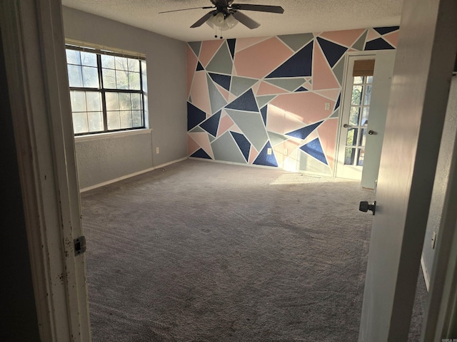 carpeted empty room featuring plenty of natural light, a textured ceiling, and ceiling fan