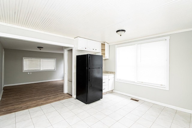 kitchen featuring black refrigerator and white cabinets