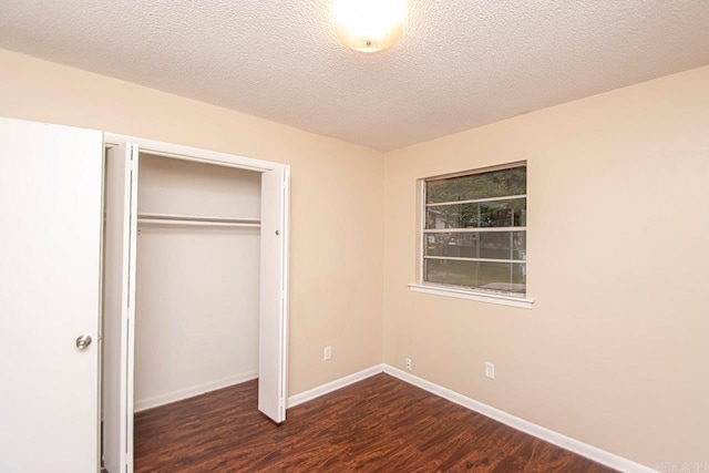 unfurnished bedroom with a textured ceiling, dark hardwood / wood-style floors, and a closet