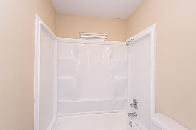 bathroom featuring tub / shower combination, toilet, and a textured ceiling