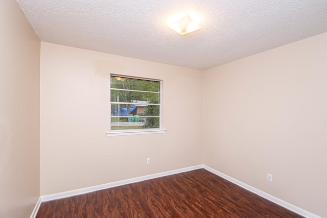 empty room with dark wood-type flooring and a textured ceiling