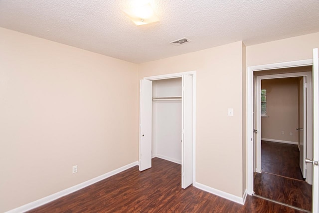 unfurnished bedroom with a closet, a textured ceiling, and dark hardwood / wood-style flooring