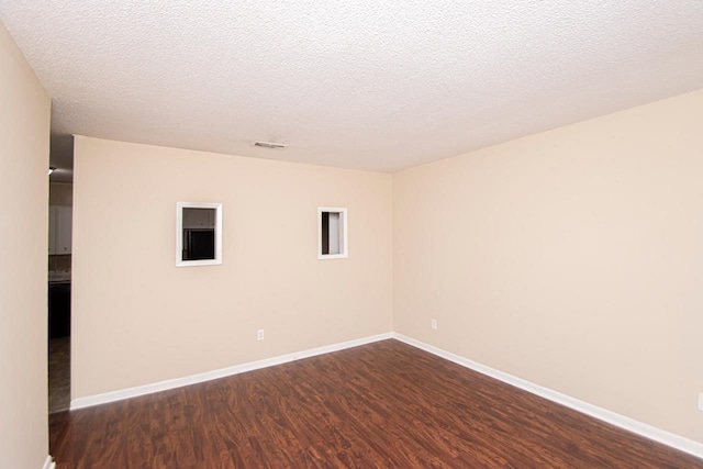 unfurnished room featuring dark wood-type flooring and a textured ceiling