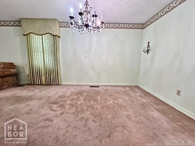 unfurnished dining area featuring a notable chandelier, carpet floors, and a textured ceiling