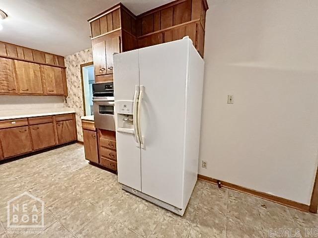 kitchen featuring white fridge with ice dispenser and stainless steel oven