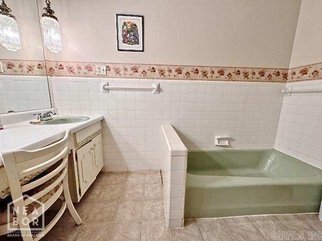 bathroom featuring a washtub, tile walls, vanity, and tile patterned flooring