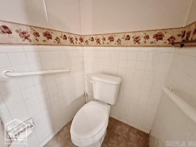 bathroom featuring toilet, tile patterned flooring, and tile walls