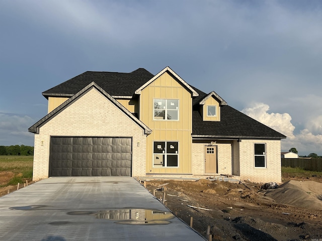 13510 Smarty Jones Dr, Scott, AR 72142 - view of front of property featuring brick siding, an attached garage, driveway, board and batten siding, and a shingled roof