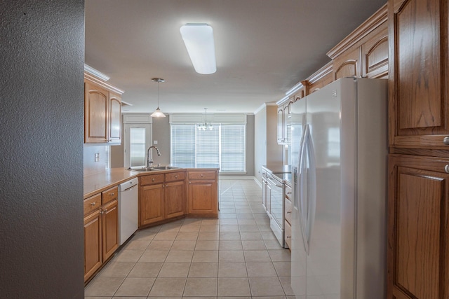 kitchen featuring pendant lighting, white appliances, sink, light tile patterned floors, and crown molding