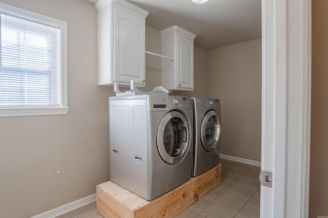 laundry room with washer and clothes dryer, a wealth of natural light, light tile patterned floors, and cabinets