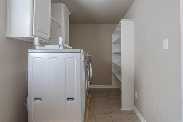 washroom with washing machine and clothes dryer, light tile patterned floors, and cabinets