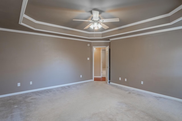 carpeted spare room with crown molding, a tray ceiling, and ceiling fan