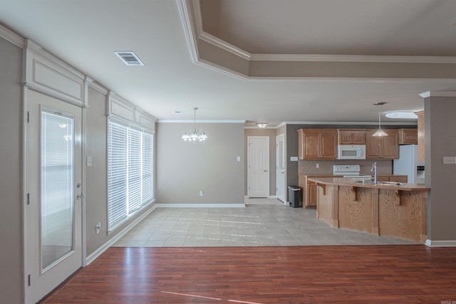 kitchen with crown molding, white appliances, and decorative light fixtures