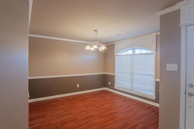 spare room featuring a notable chandelier, ornamental molding, and dark wood-type flooring