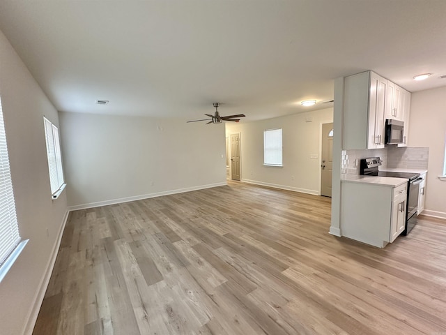 kitchen with tasteful backsplash, white cabinets, light wood-type flooring, ceiling fan, and electric stove