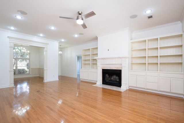 unfurnished living room with light hardwood / wood-style floors, ceiling fan with notable chandelier, and ornamental molding