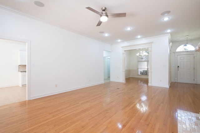 unfurnished living room with ceiling fan with notable chandelier, light hardwood / wood-style flooring, and crown molding