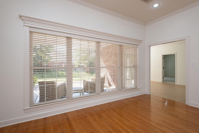 empty room with plenty of natural light, hardwood / wood-style flooring, and ornamental molding