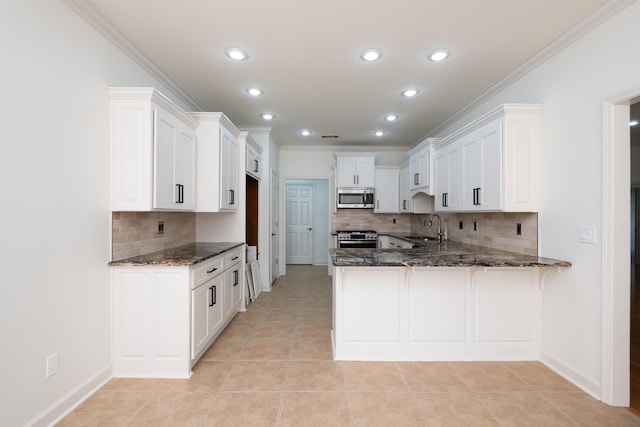 kitchen featuring kitchen peninsula, sink, dark stone counters, ornamental molding, and stainless steel appliances