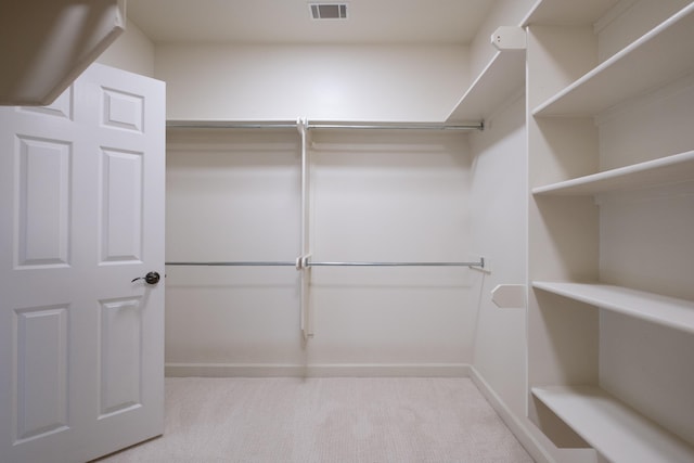 walk in closet with light carpet