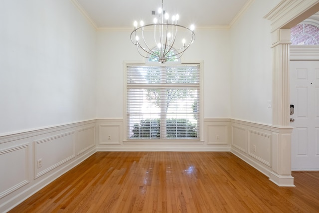 unfurnished dining area featuring light hardwood / wood-style flooring, ornamental molding, and an inviting chandelier