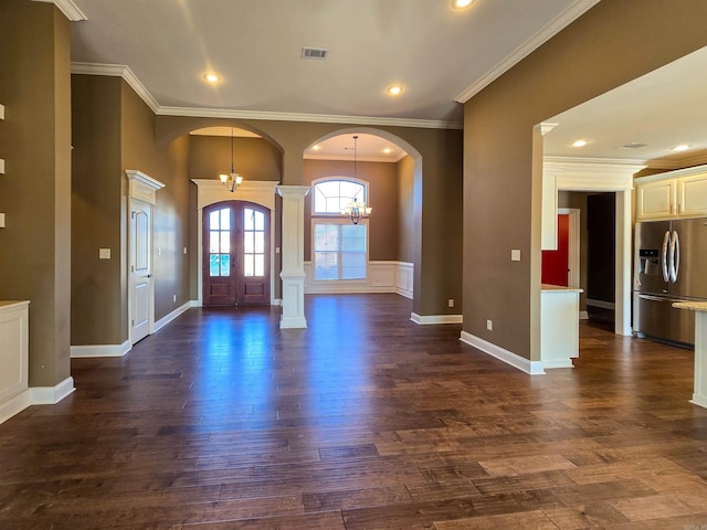 foyer featuring an inviting chandelier, dark wood-type flooring, ornamental molding, and ornate columns