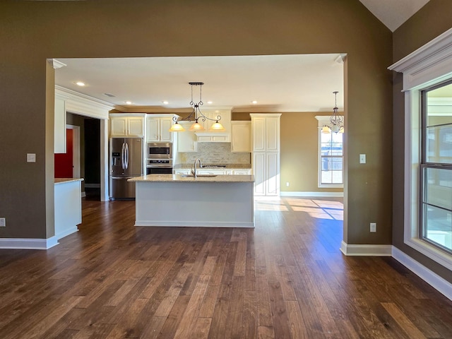 kitchen with light stone counters, vaulted ceiling, hanging light fixtures, stainless steel appliances, and backsplash