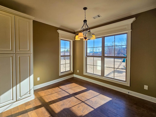 unfurnished dining area with dark hardwood / wood-style flooring, crown molding, and a chandelier