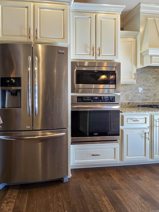 kitchen featuring premium range hood, dark wood-type flooring, appliances with stainless steel finishes, light stone countertops, and decorative backsplash