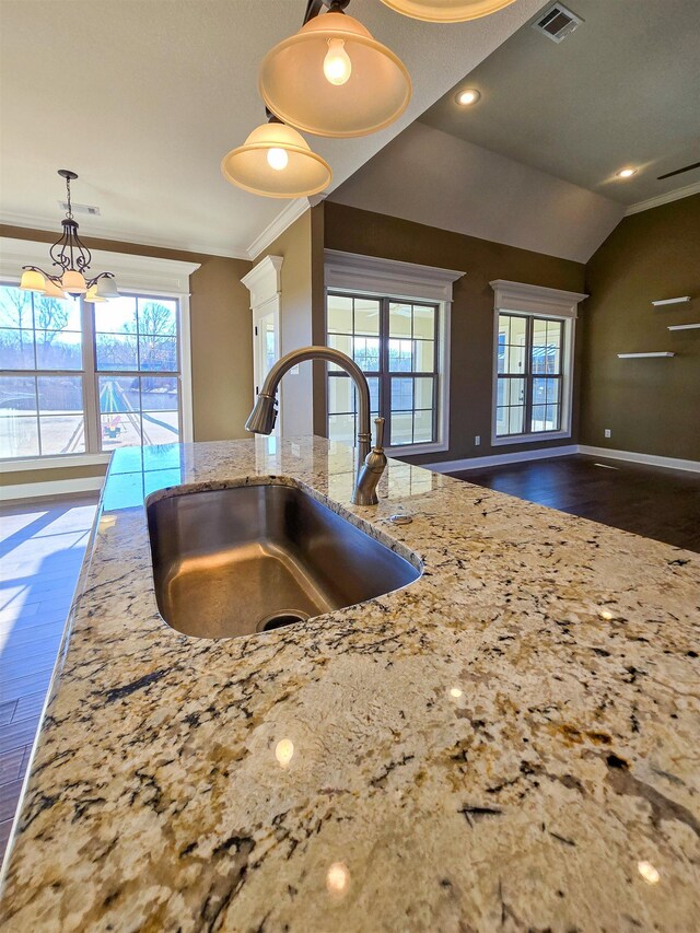 kitchen featuring lofted ceiling, sink, crown molding, pendant lighting, and a healthy amount of sunlight