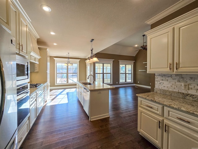 kitchen with appliances with stainless steel finishes, decorative light fixtures, sink, decorative backsplash, and light stone counters