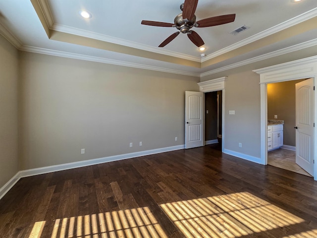 unfurnished bedroom with connected bathroom, crown molding, a tray ceiling, dark hardwood / wood-style floors, and ceiling fan