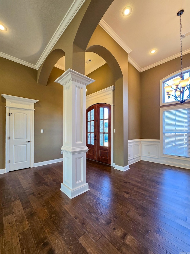 interior space featuring crown molding, an inviting chandelier, dark hardwood / wood-style floors, french doors, and ornate columns