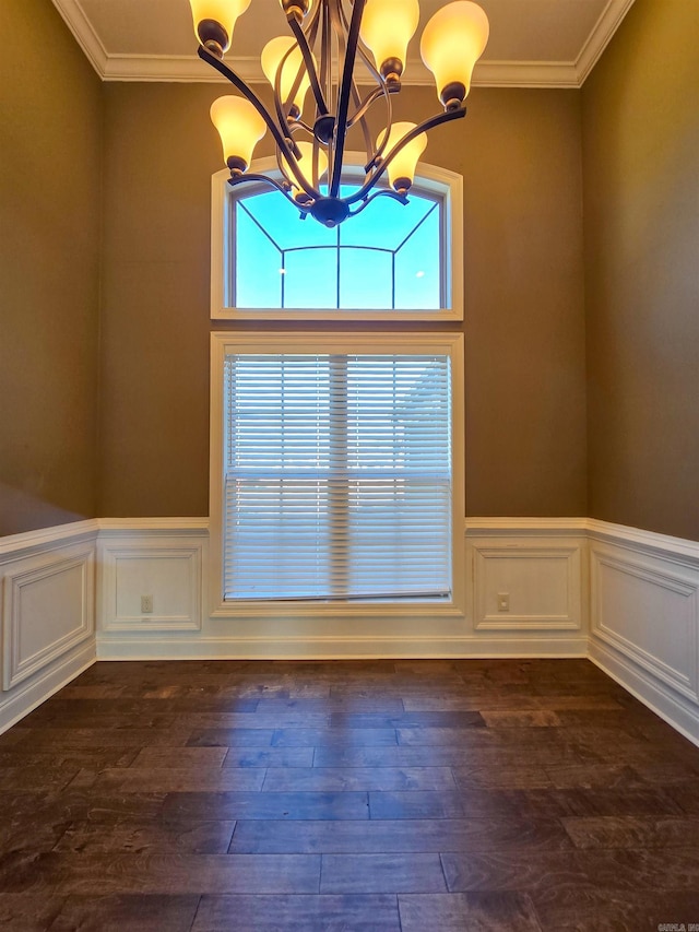 unfurnished dining area with dark wood-type flooring, ornamental molding, and a notable chandelier