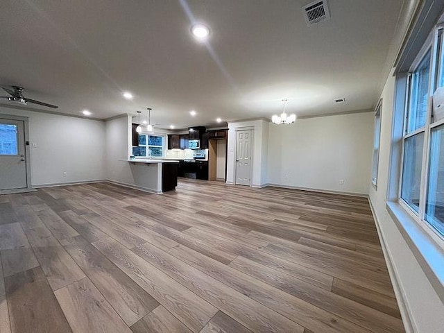 unfurnished living room featuring hardwood / wood-style flooring, ceiling fan with notable chandelier, and ornamental molding