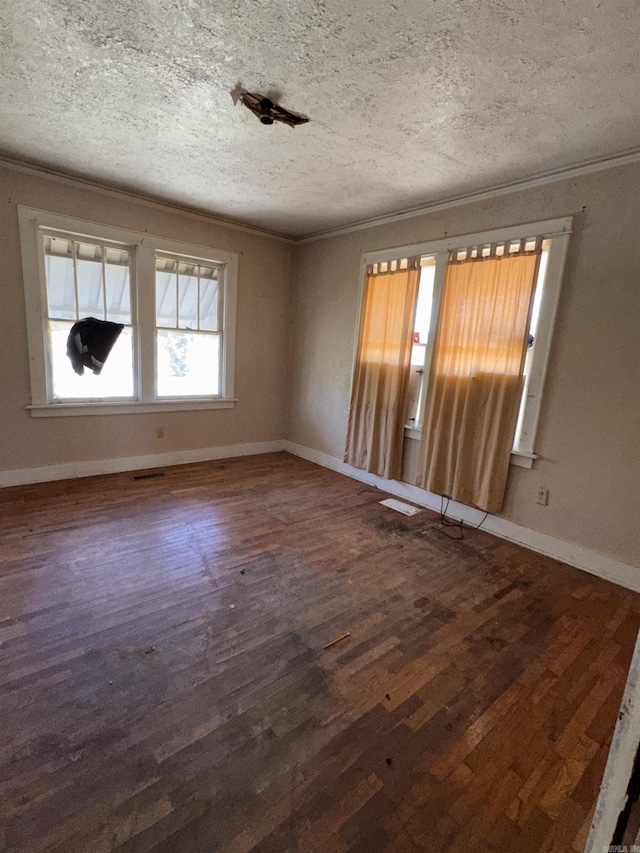 empty room with dark wood-type flooring, ornamental molding, and a textured ceiling