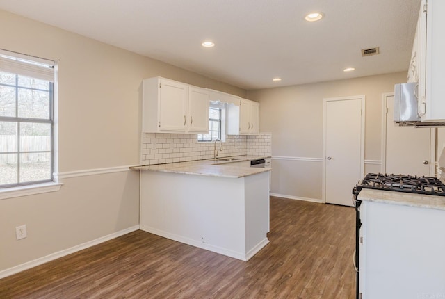 kitchen with dark wood-type flooring, a wealth of natural light, white cabinets, and range with gas stovetop