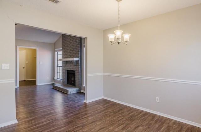 interior space featuring a notable chandelier, a brick fireplace, dark hardwood / wood-style flooring, and lofted ceiling