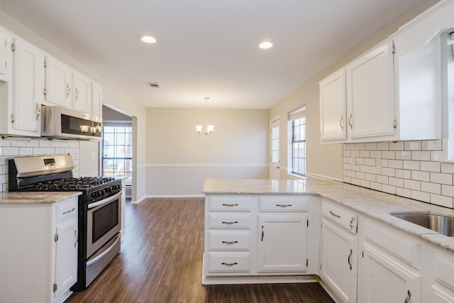 kitchen with pendant lighting, white cabinetry, stainless steel appliances, decorative backsplash, and kitchen peninsula