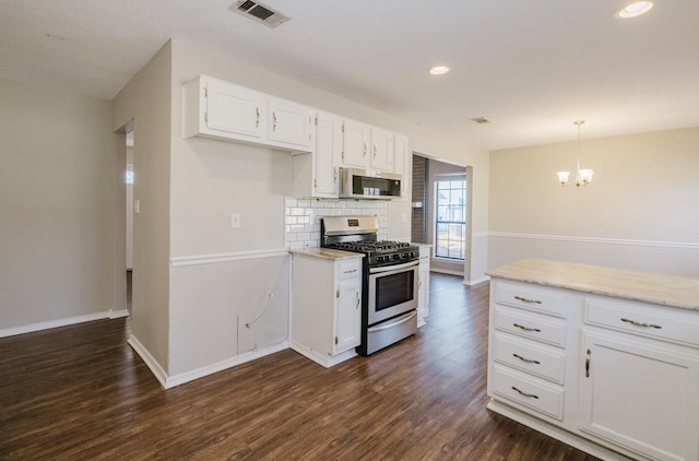 kitchen with appliances with stainless steel finishes, white cabinetry, dark hardwood / wood-style flooring, decorative backsplash, and hanging light fixtures