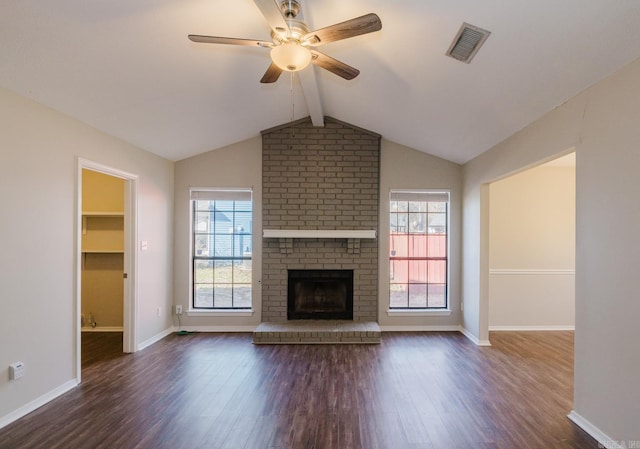 unfurnished living room with a brick fireplace, plenty of natural light, and dark hardwood / wood-style flooring